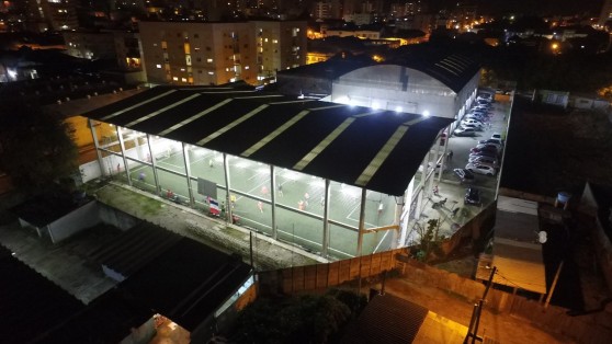 Ginásio à noite com a quadra society iluminada