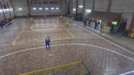Partida de futsal em andamento na quadra de parquet